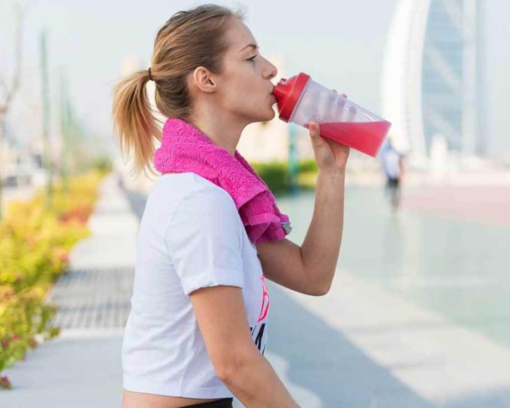 woman drinking protein shake after jogging